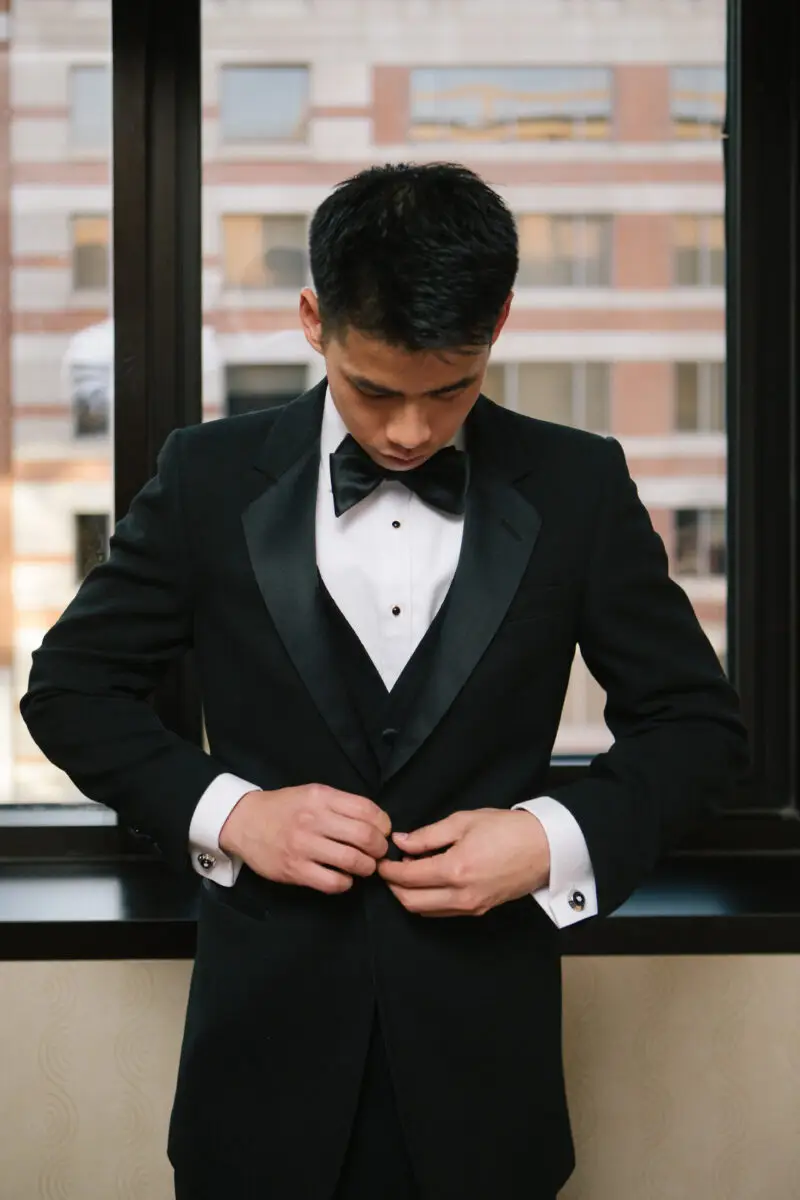 Groom buttoning his tuxedo jacket. Howerton+Wooten Events. The Enlightened Creative.