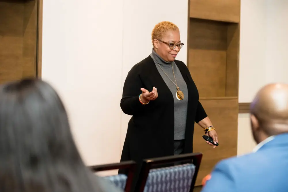 Kawania Wooten at a speaking engagement with a white and brown background. The Enlightened Creative.